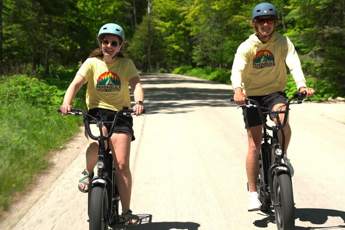 two people riding bikes down a dirt road