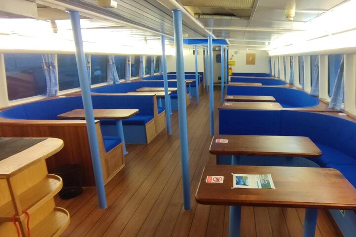 a train car with blue seats and wooden tables
