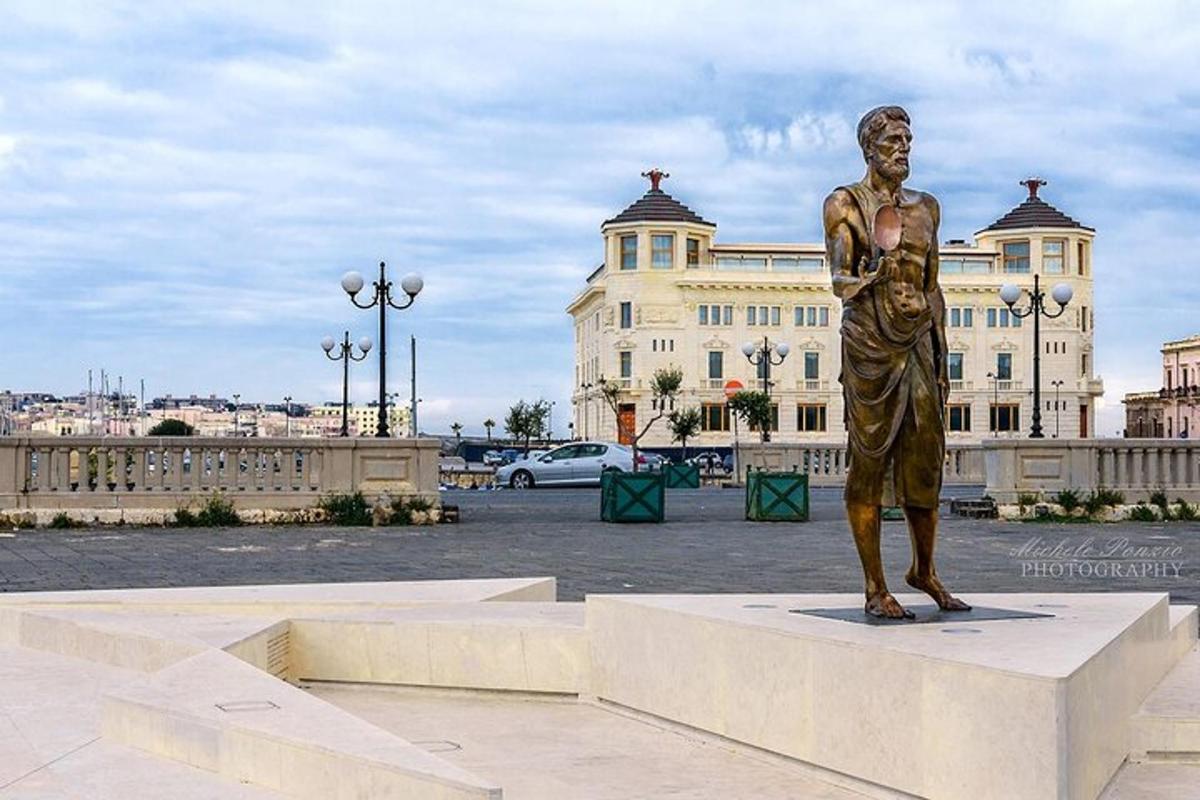 una statua di un uomo in piedi su un piedistallo di fronte a un edificio