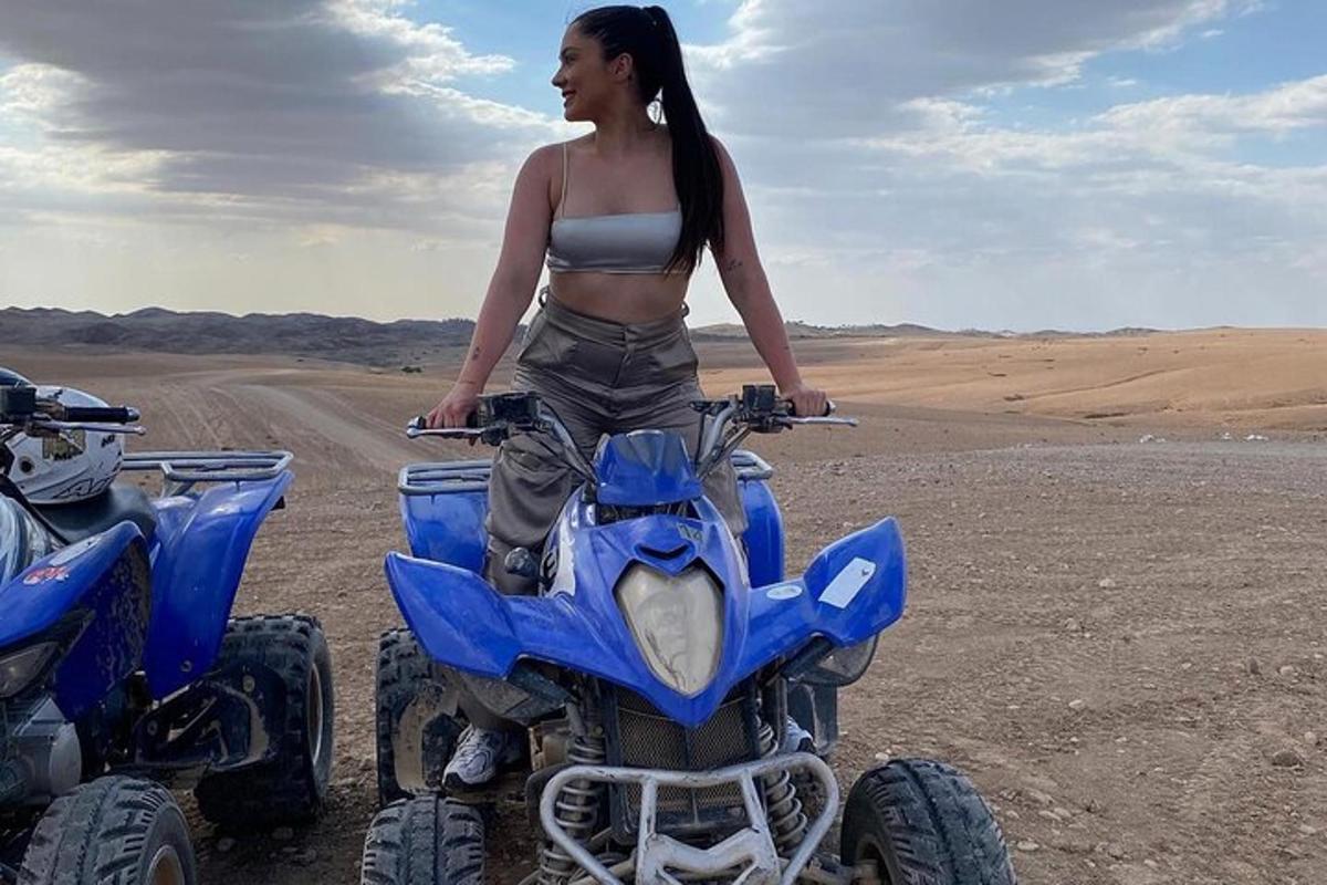 a woman is sitting on a four wheeler in the desert