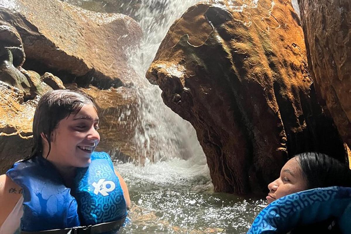 two girls in the water in front of a waterfall