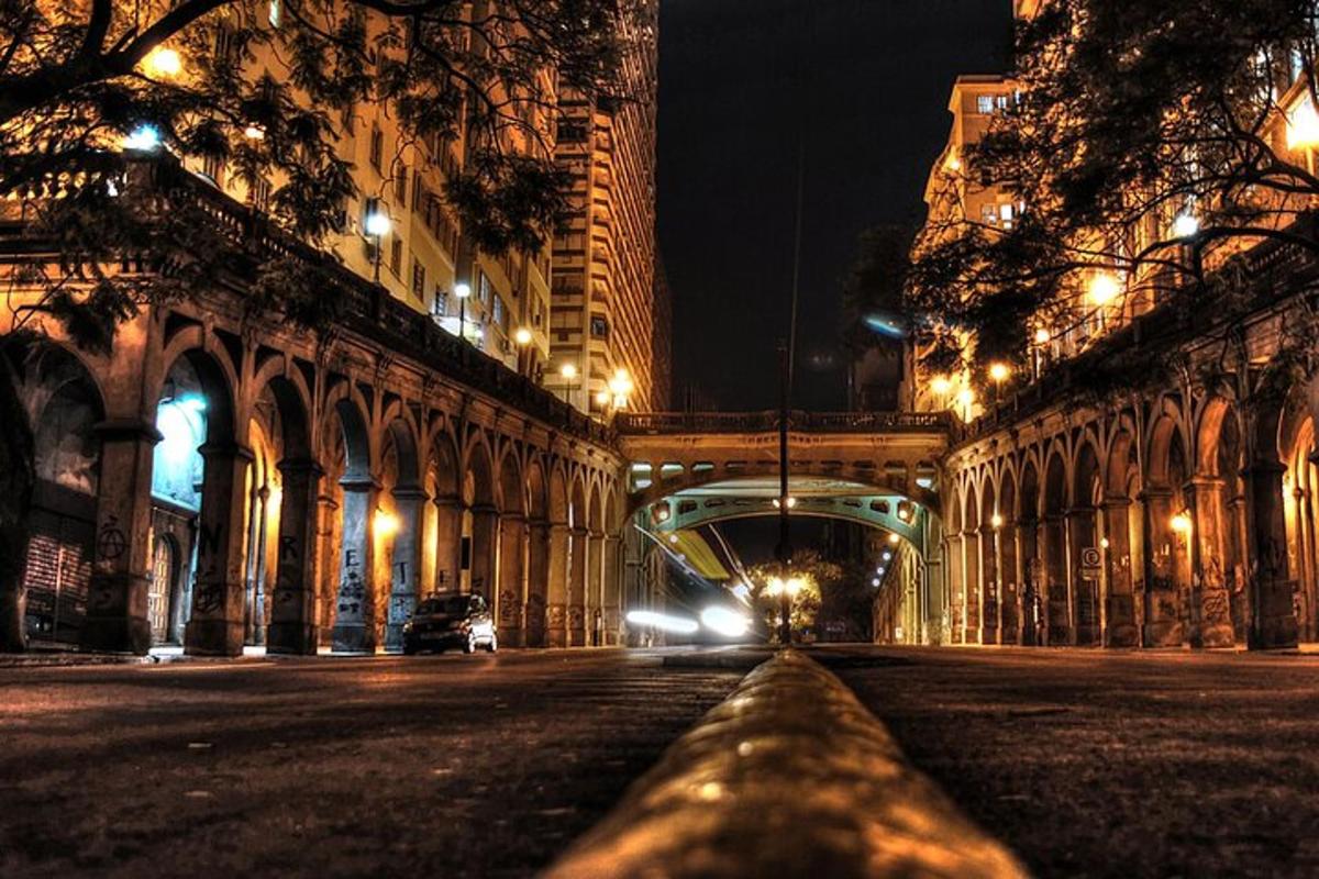 a city street at night with a bridge and buildings