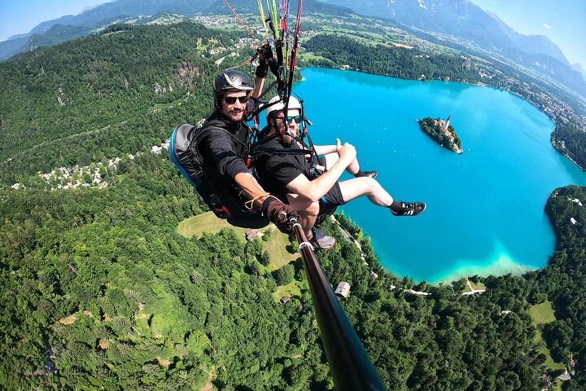 dva lidé letí na padáku nad jezerem