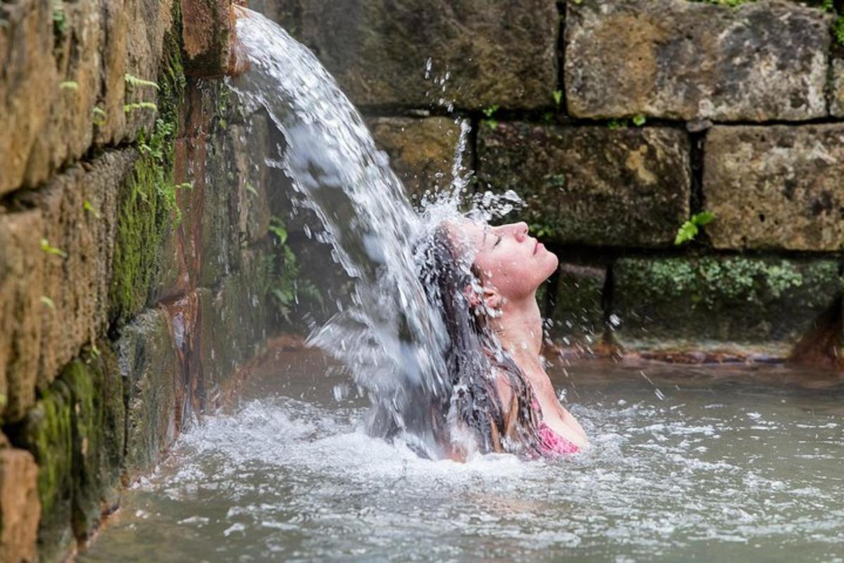 eine Frau, die im Wasser unter einem Wasserfall liegt