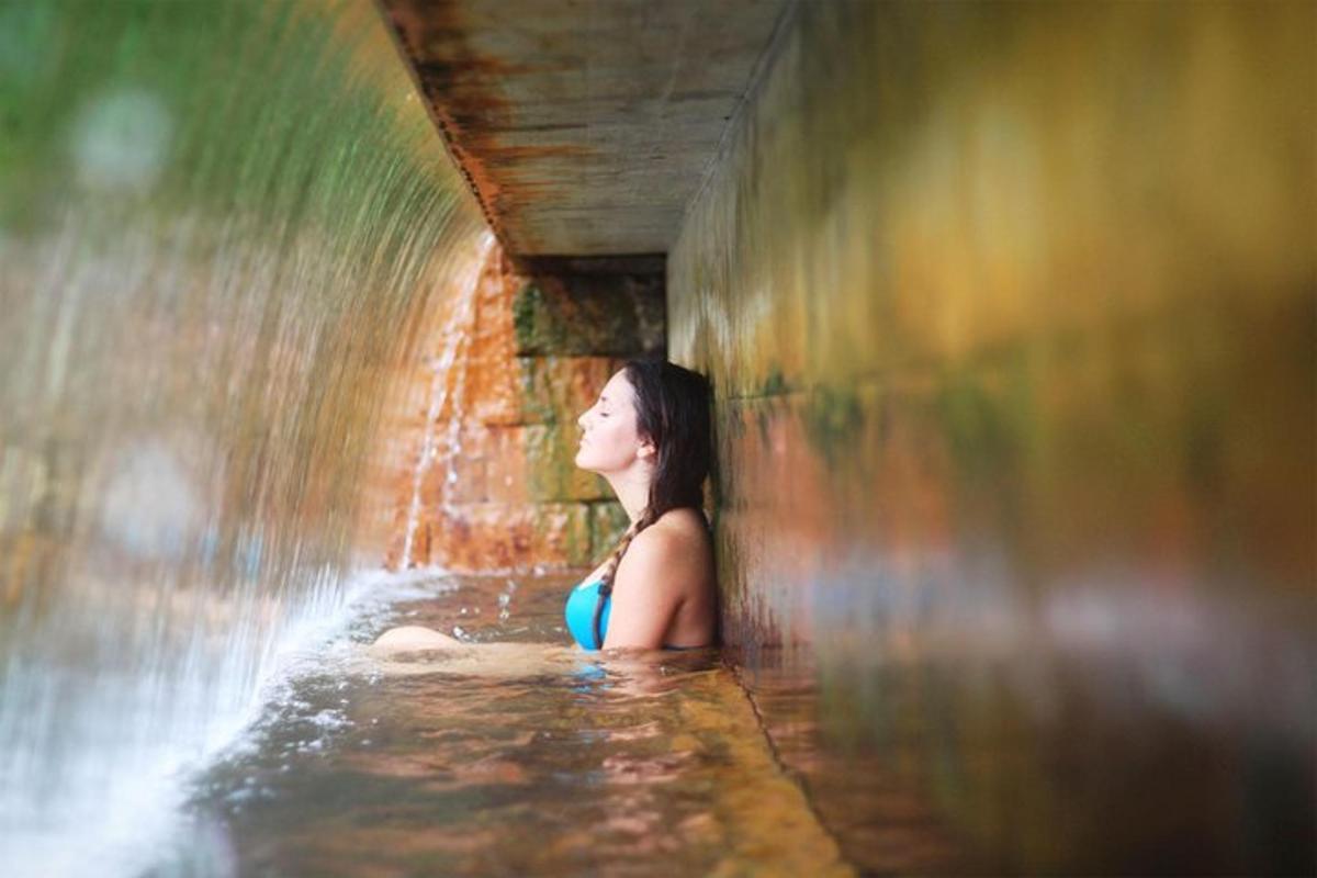 eine Frau sitzt vor einem Wasserfall
