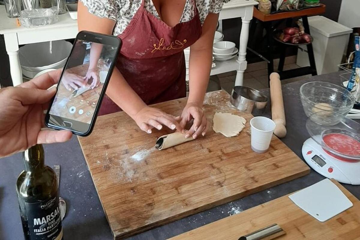 Una persona tomando una fotografía de una persona cortando comida en una tabla de cortar.