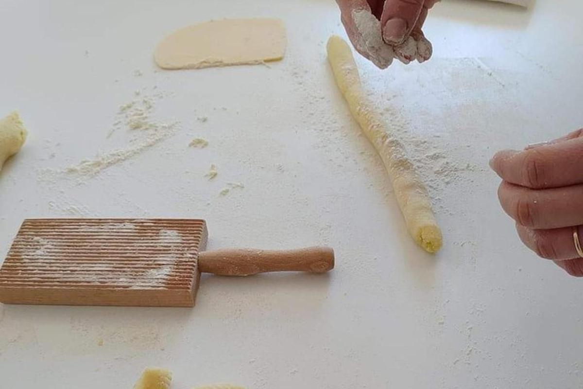 uma pessoa fazendo uma massa em uma tábua de corte com um rolo de massa