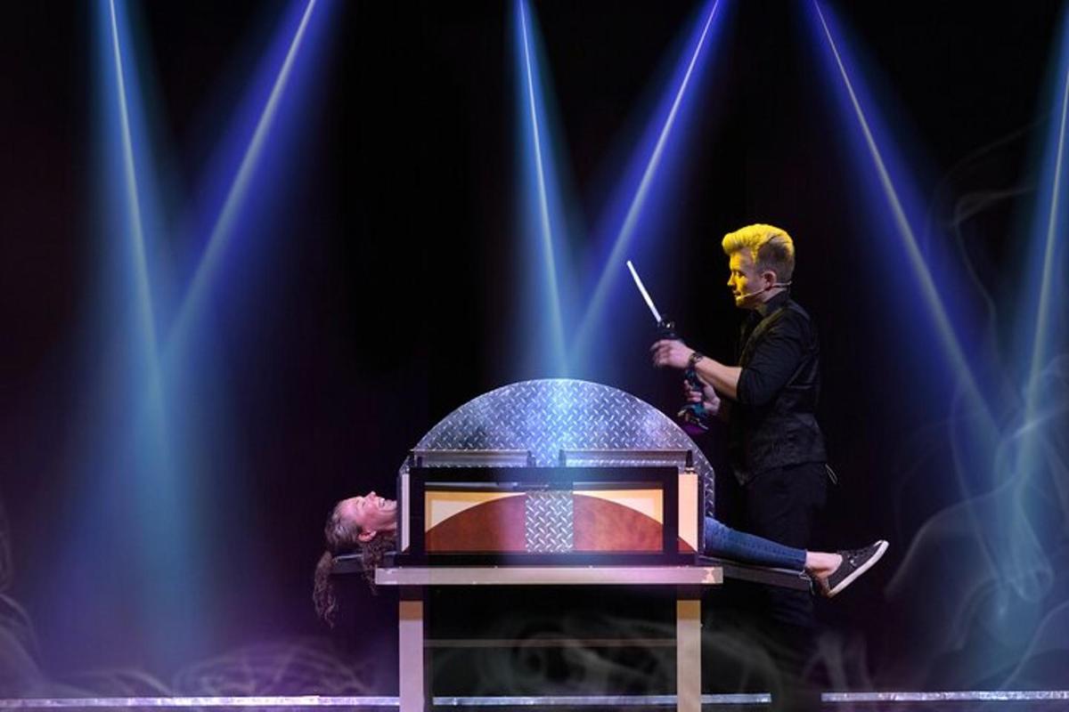 a man standing on a stage with a person sitting on a chair