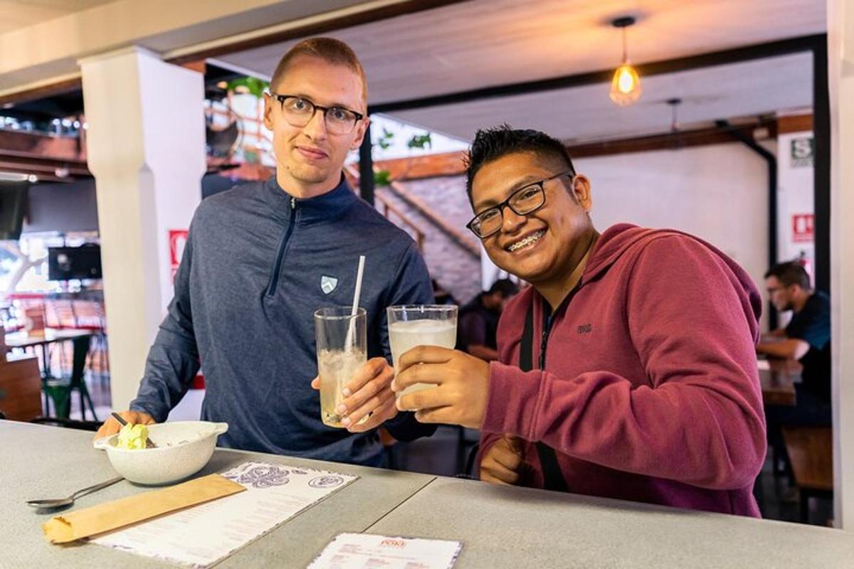 tveir menn sitja við borð og halda á drykk