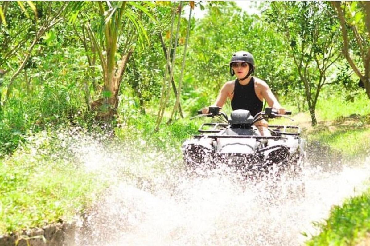 seorang pria mengendarai ATV melewati air