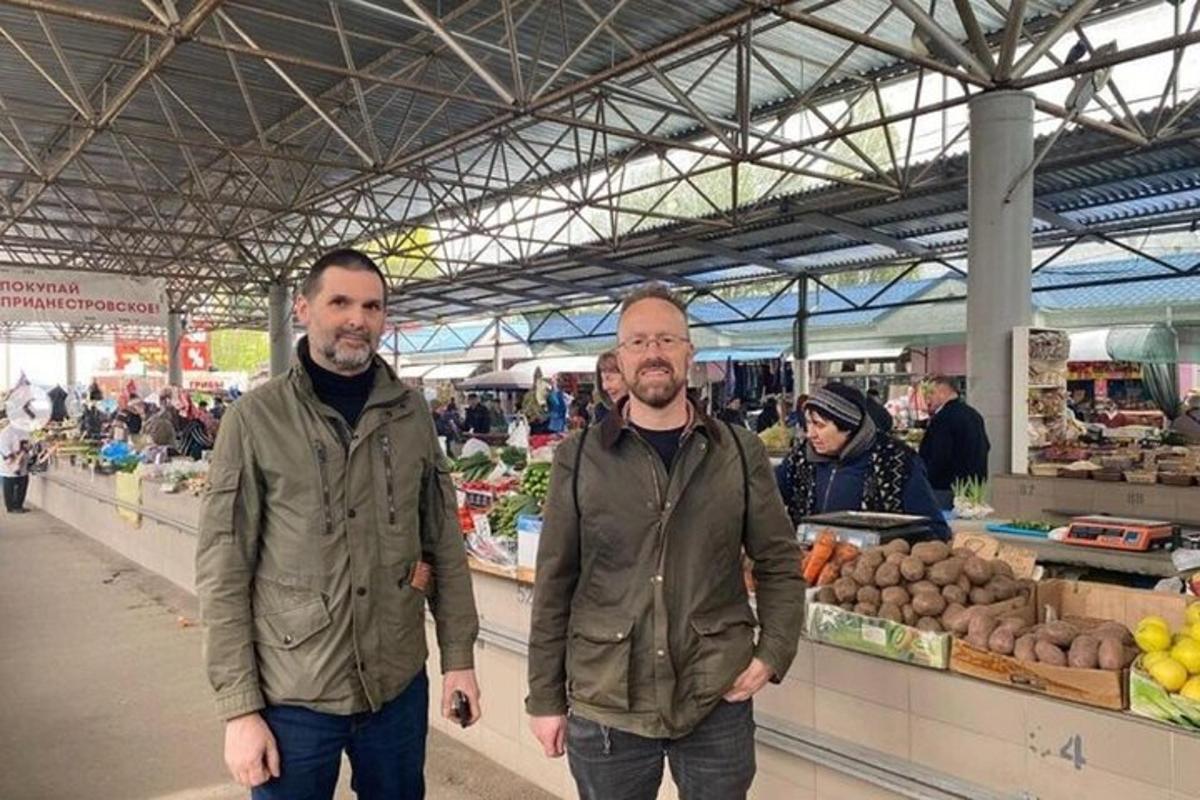 due uomini in piedi davanti a un mercato agricolo
