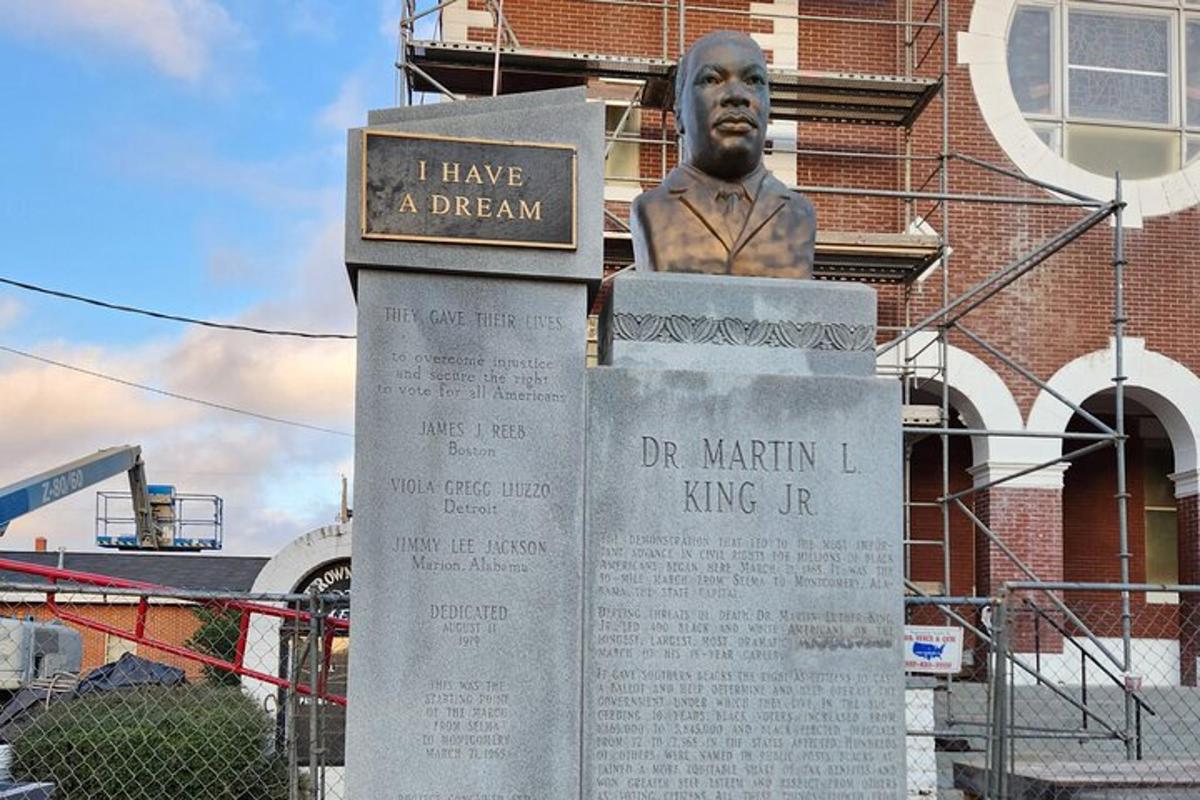 a statue of a man sitting on top of a sign