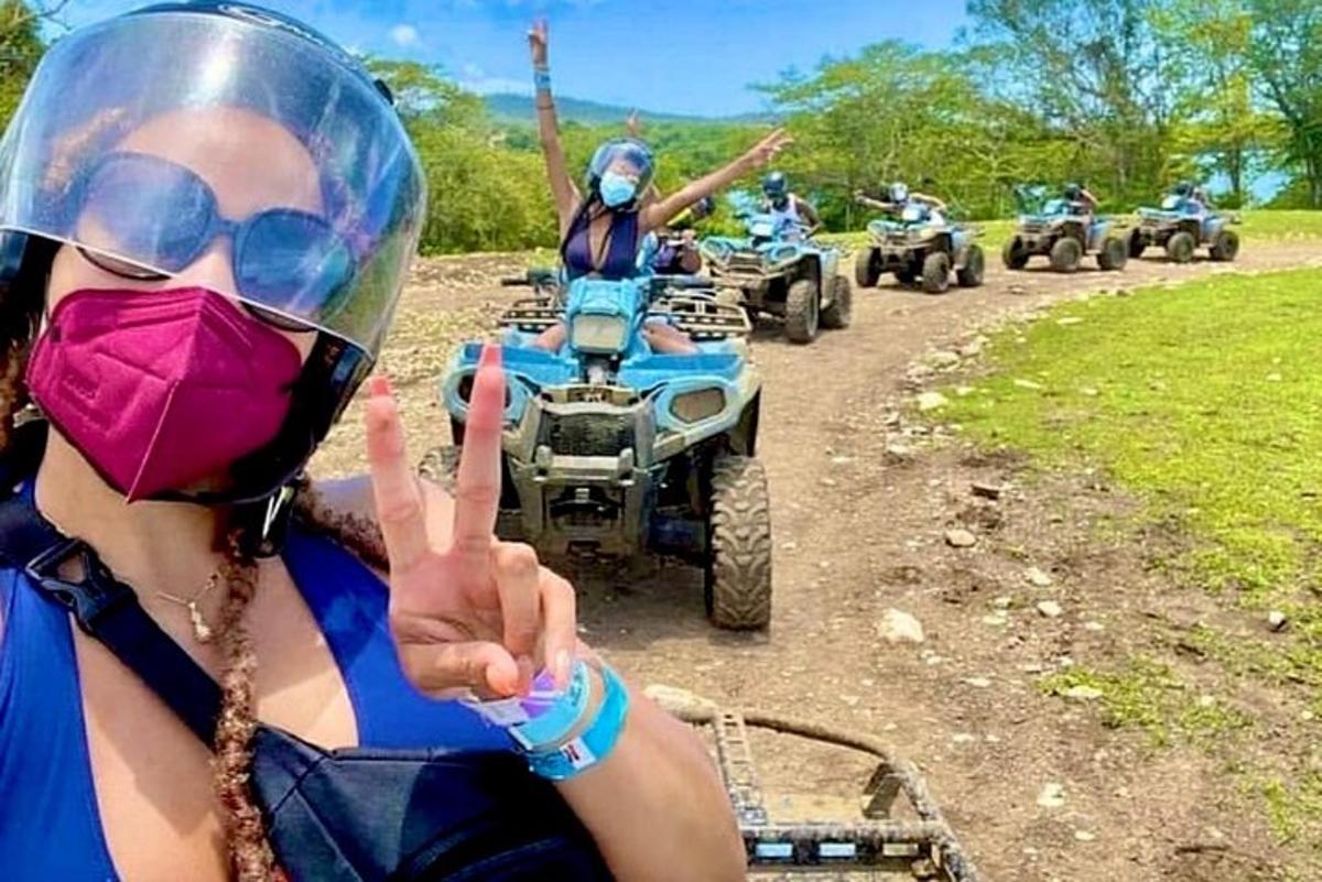 una dona amb una mascareta fent el senyal de la pau mentre condueix un quad