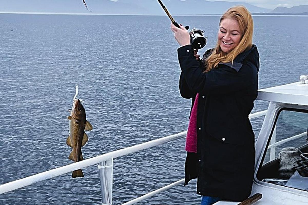 una donna che tiene in mano un pesce su una barca