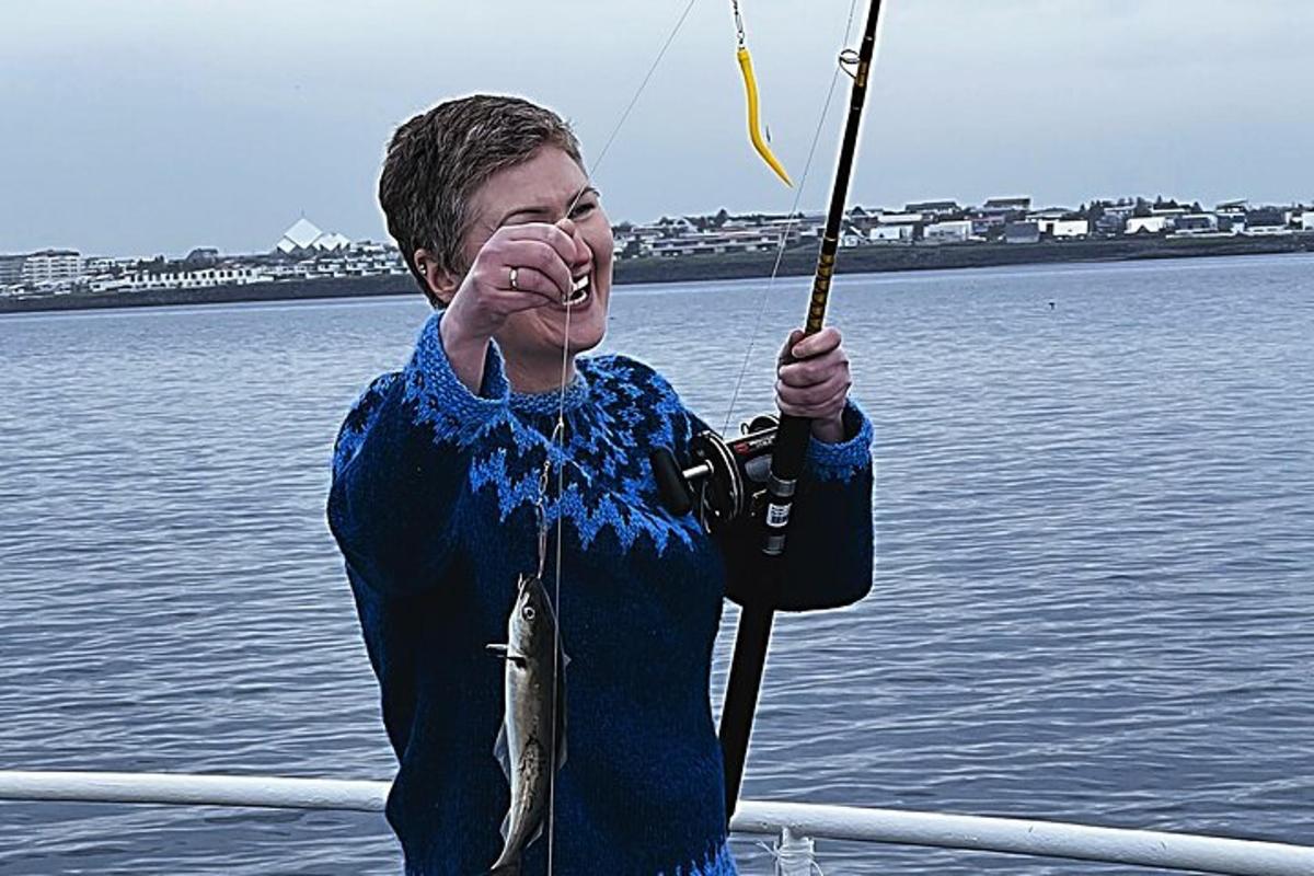 un uomo che tiene un pesce su un palo su una barca