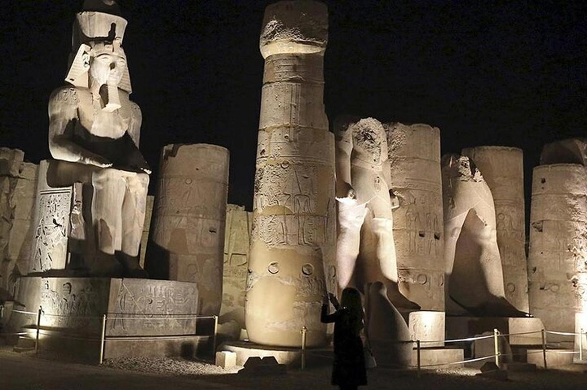 una persona in piedi davanti a una statua di notte