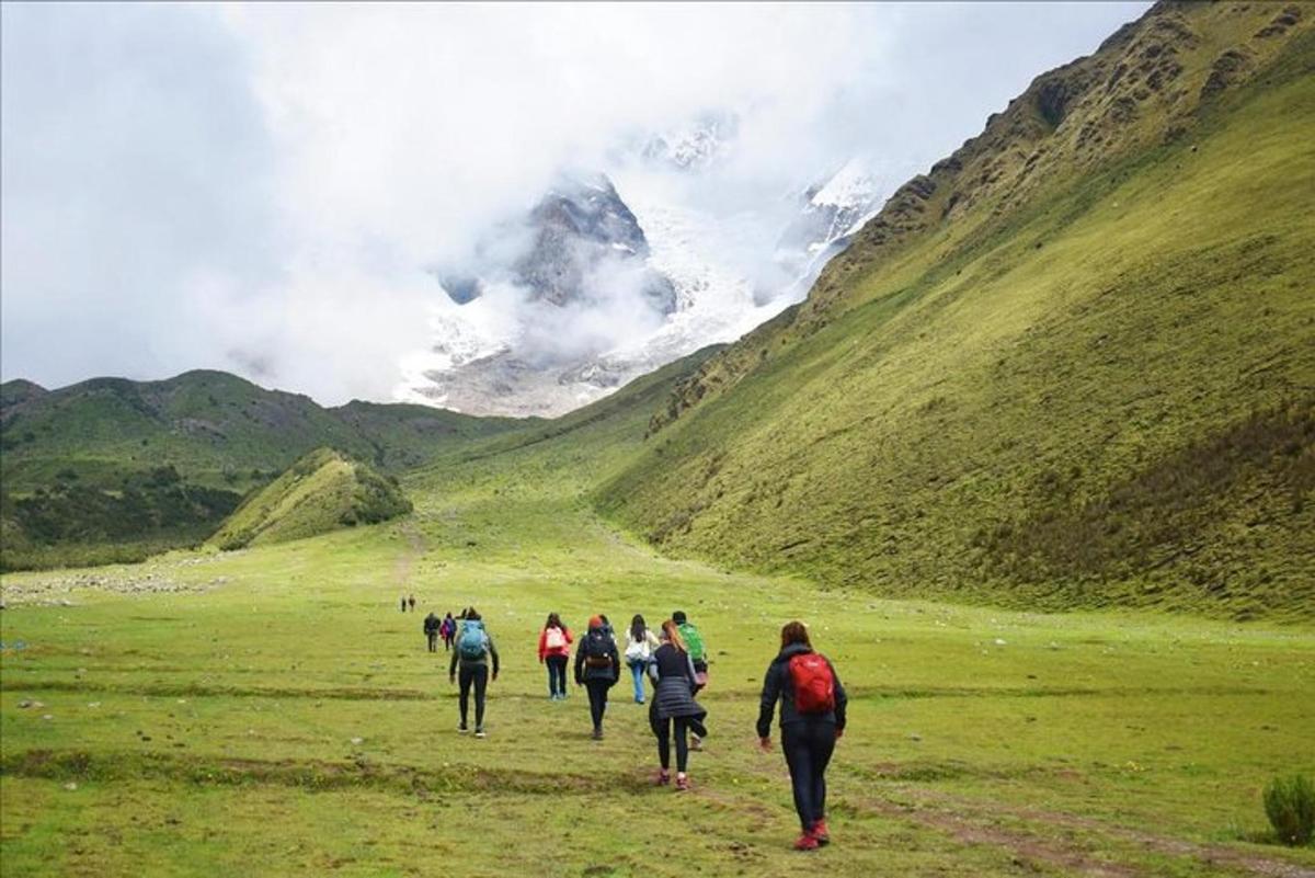 um grupo de pessoas caminhando por um campo com montanhas