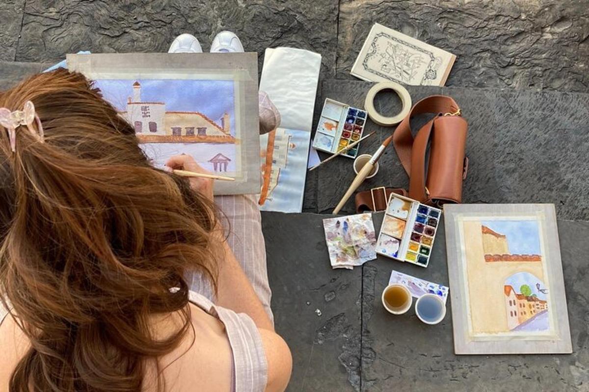 Una mujer está sentada en el suelo con su pintura.