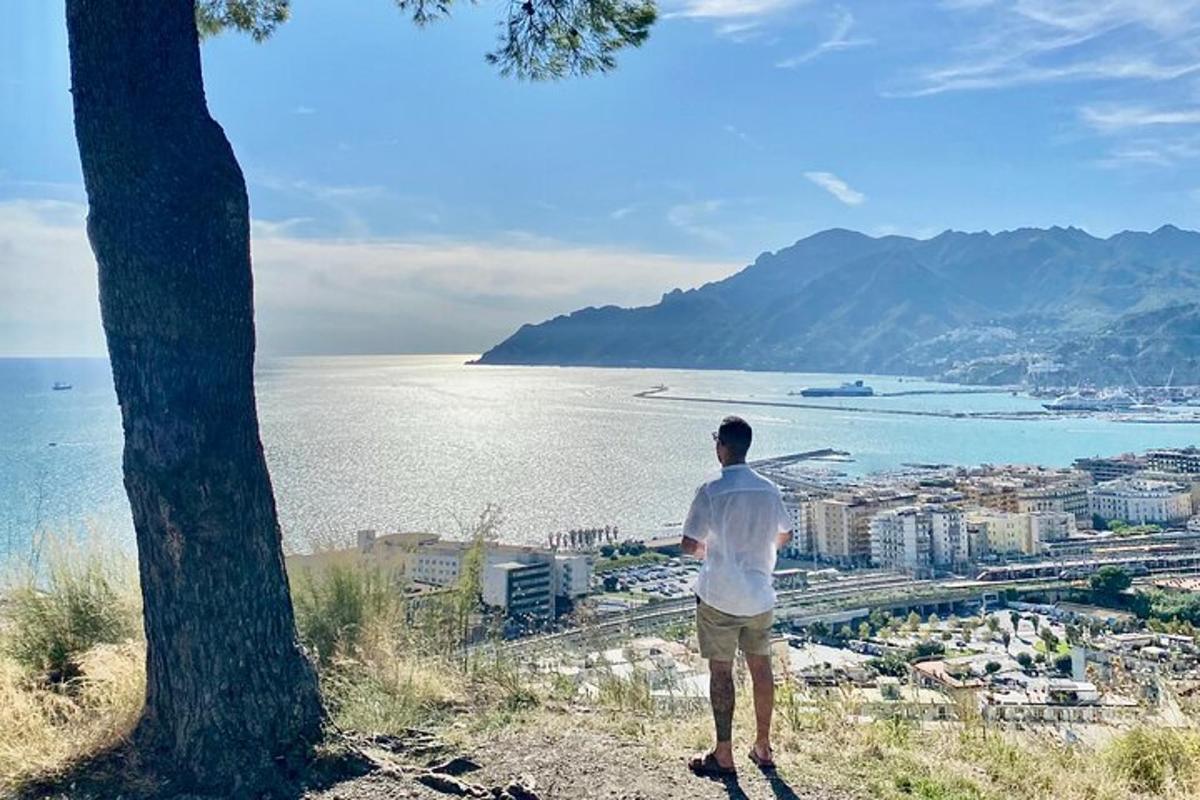 a man standing on top of a hill looking at the ocean