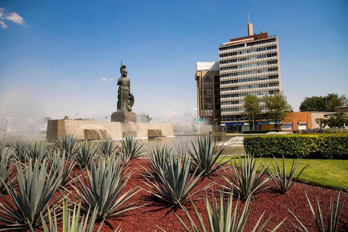 a statue in the middle of a park with plants