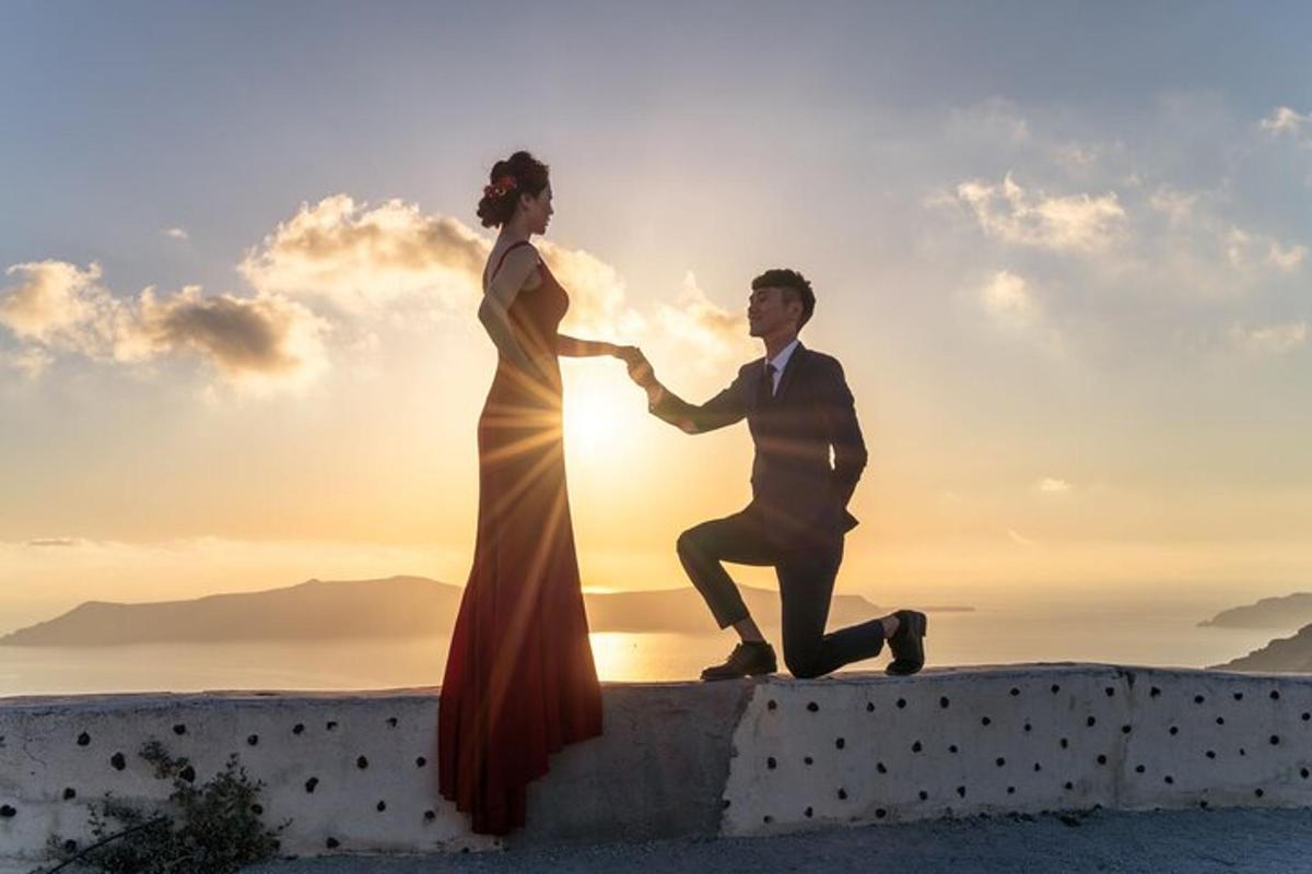 Una novia y un novio de pie en un muro frente al atardecer.