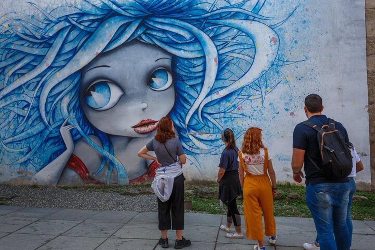 a group of people standing in front of a mural