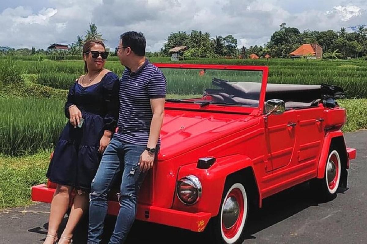 Un hombre y una mujer de pie junto a un coche rojo.