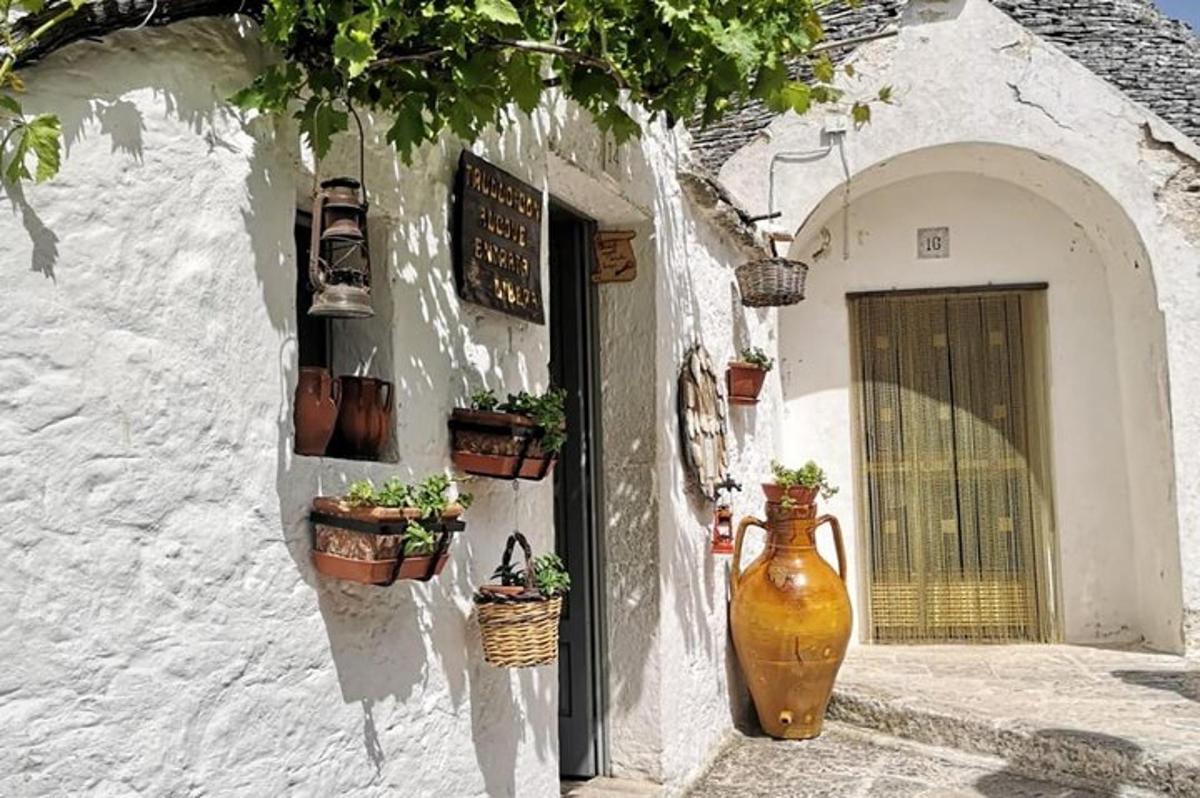 a large vase sitting on the side of a building with potted plants