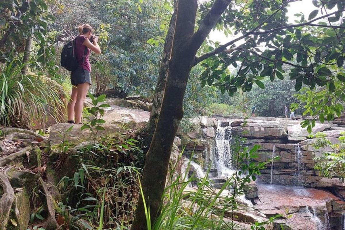 a man with a backpack taking a picture of a waterfall