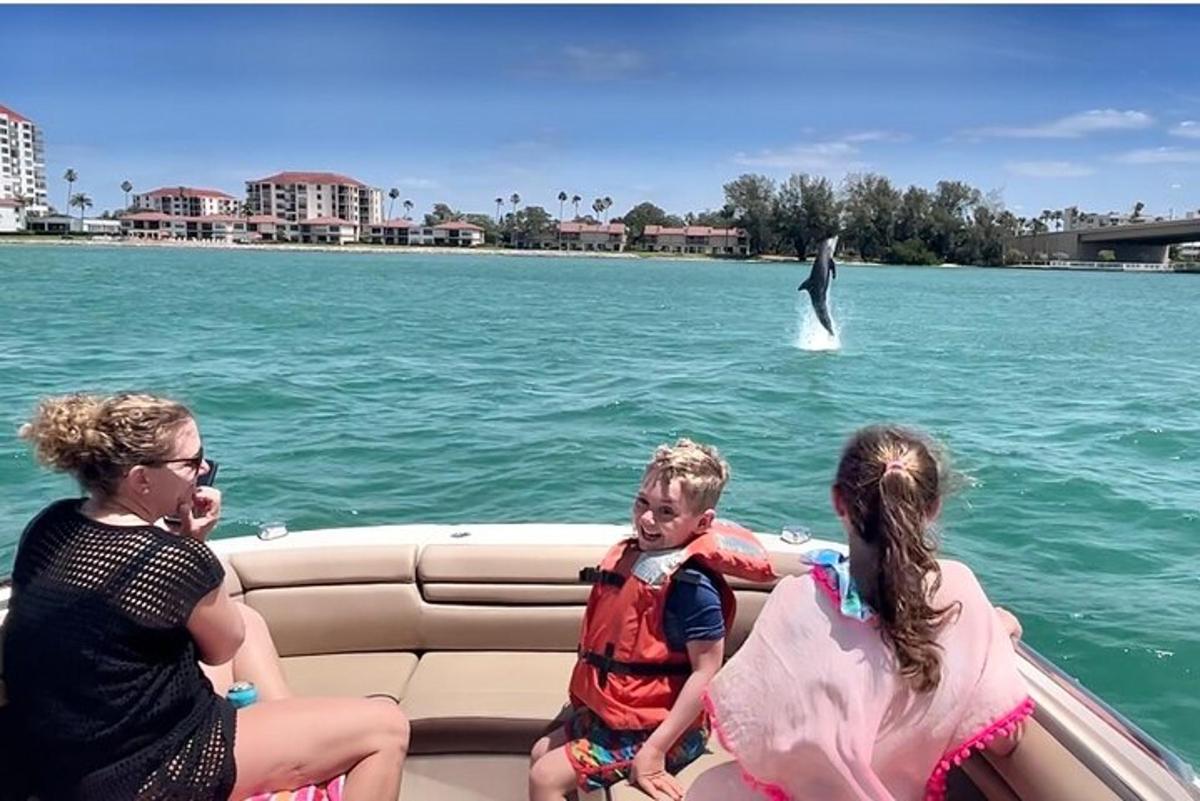 Un grupo de personas en un barco mirando un delfín.