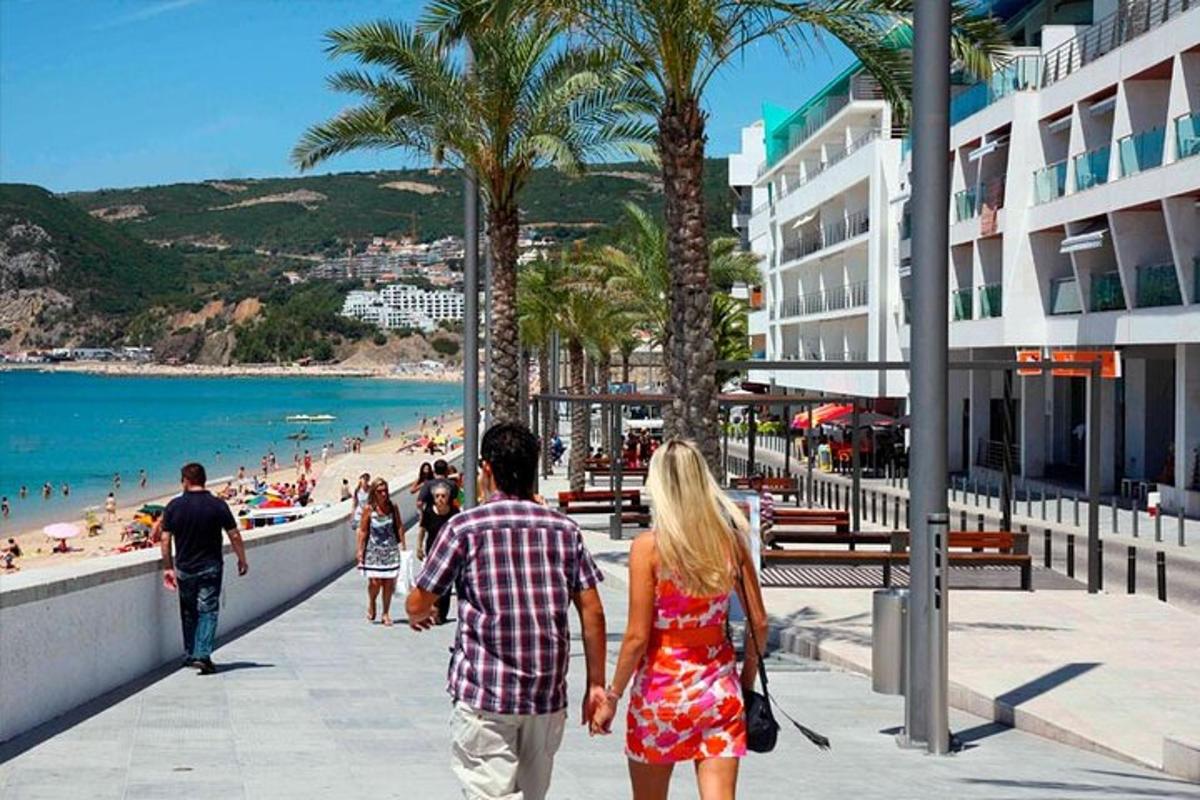 un uomo e una donna camminano lungo un marciapiede vicino alla spiaggia