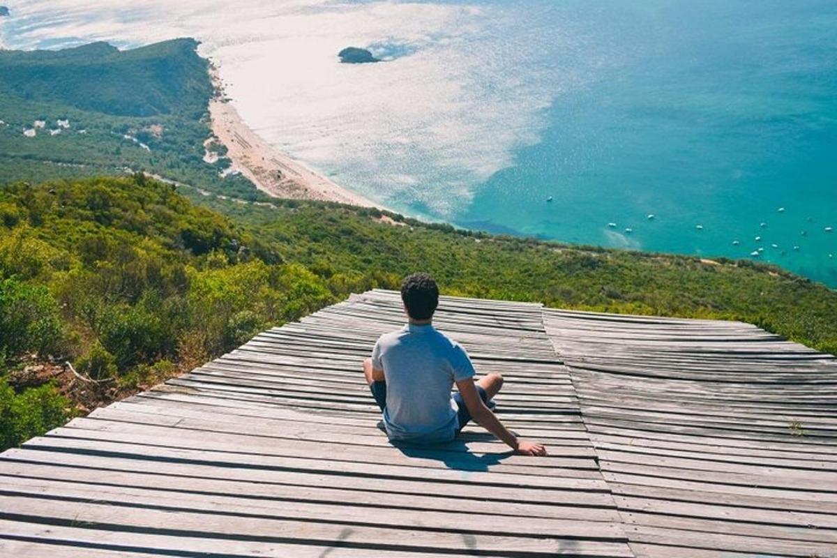 un uomo seduto su una passerella che guarda l'oceano