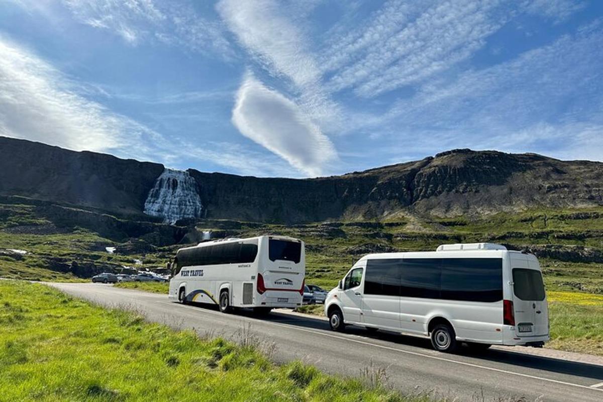 two white vans are driving down a road