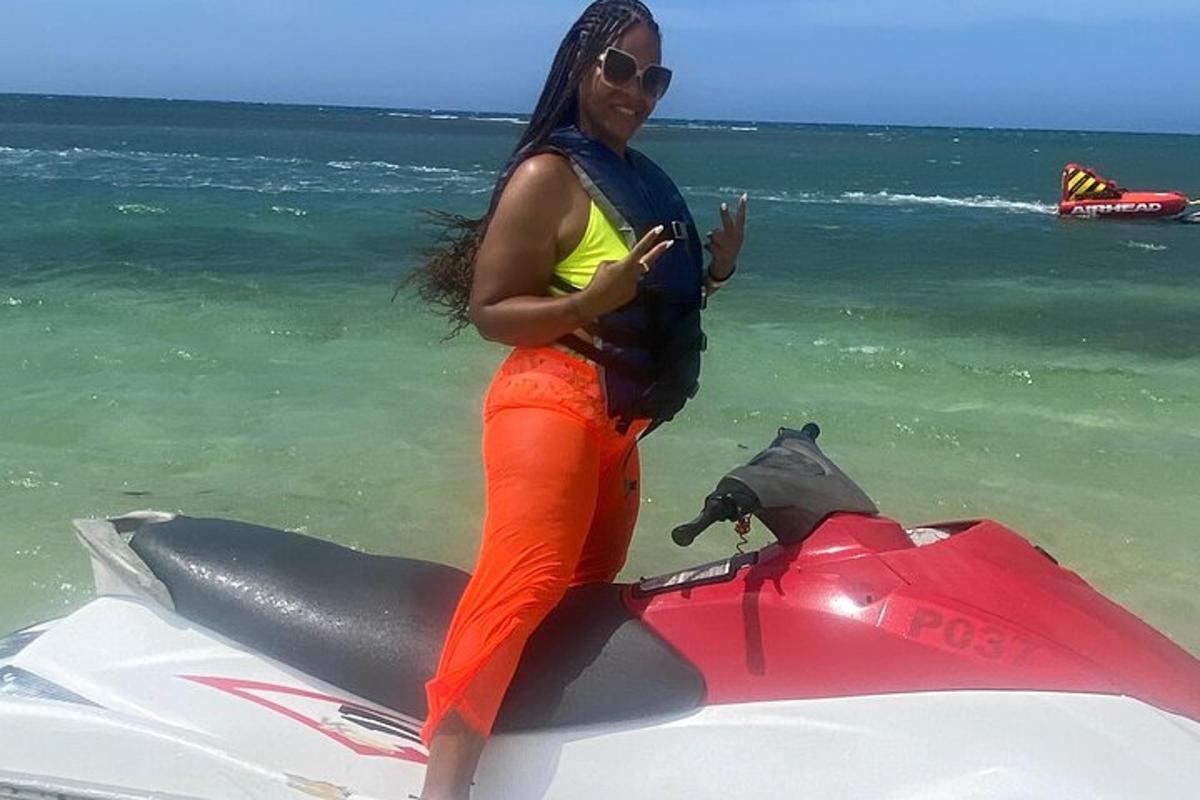 Una mujer parada en una moto acuática en la playa