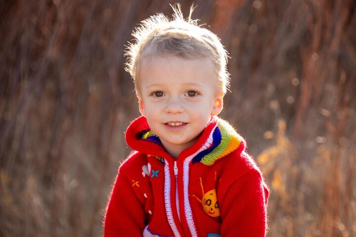 Un niño pequeño con un suéter rojo está sonriendo