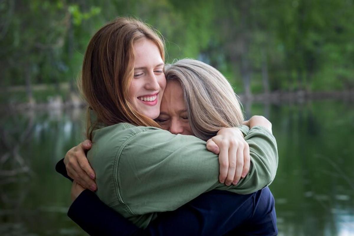 Dos mujeres abrazándose frente a un lago