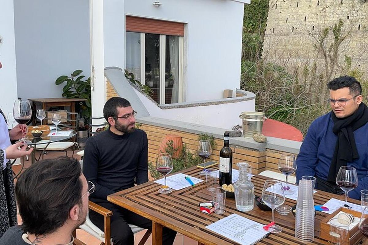 um grupo de pessoas sentadas ao redor de uma mesa com taças de vinho