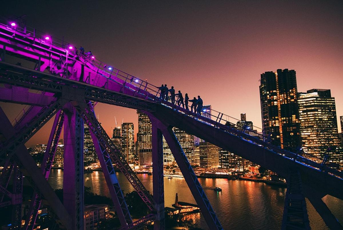 Gente caminando por un puente sobre una ciudad por la noche