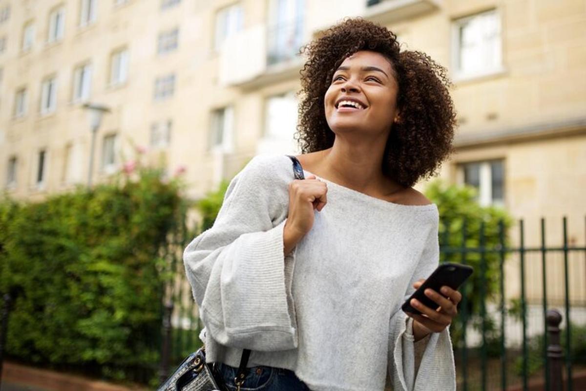 eine Frau lächelt, während sie ein Mobiltelefon hält
