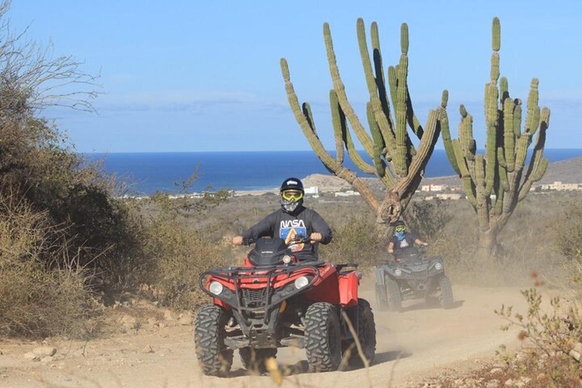 due persone che guidano un quad su una strada sterrata
