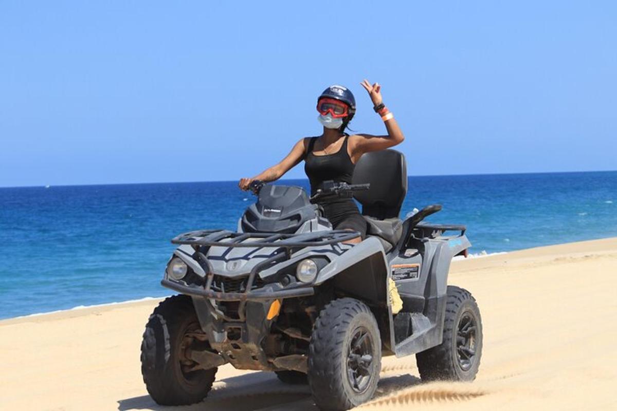 una donna su un quad sulla spiaggia