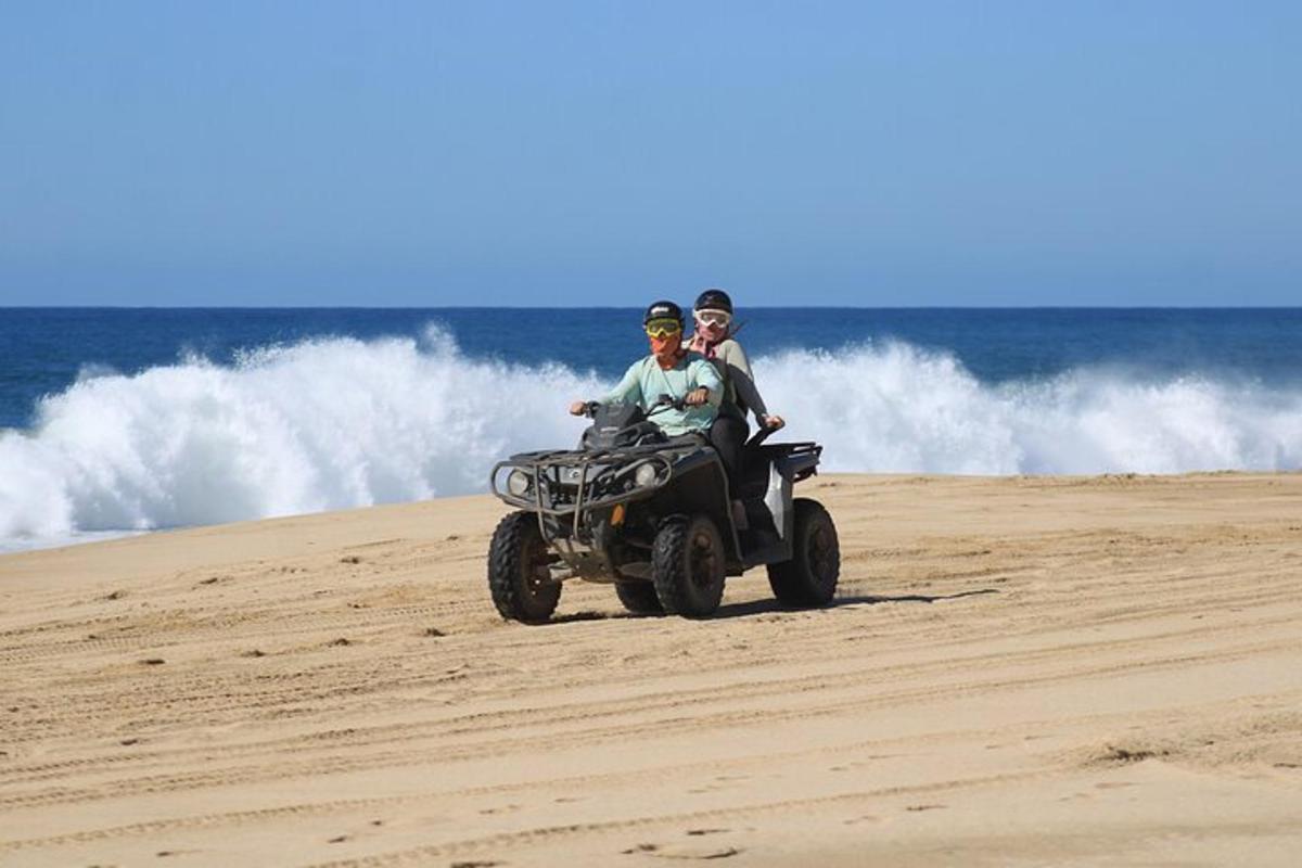 due persone in sella a un quad sulla spiaggia
