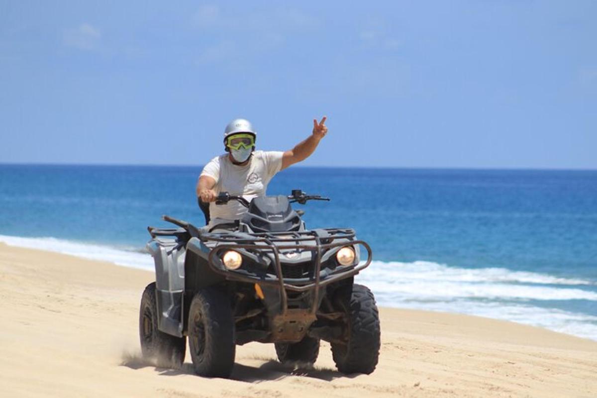 un uomo in sella a un quad sulla spiaggia