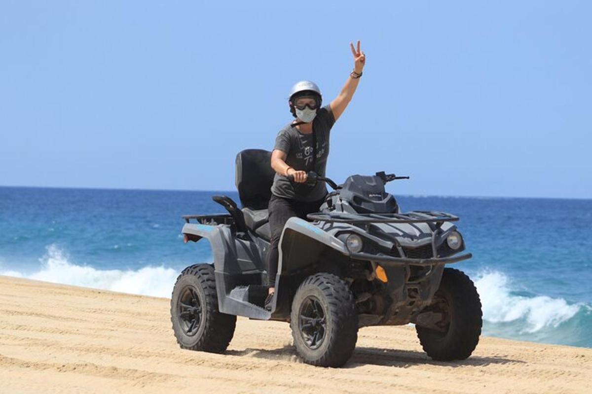 un uomo in sella a un quad sulla spiaggia