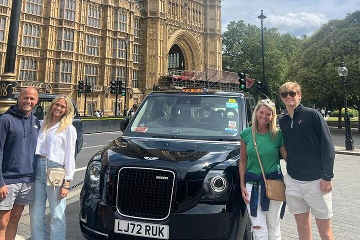 група людей стоїть перед чорним автомобілем