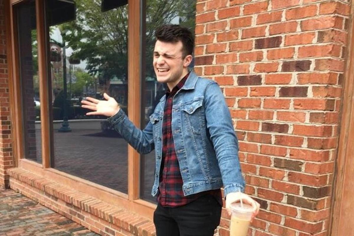 a man standing in front of a brick building holding a drink