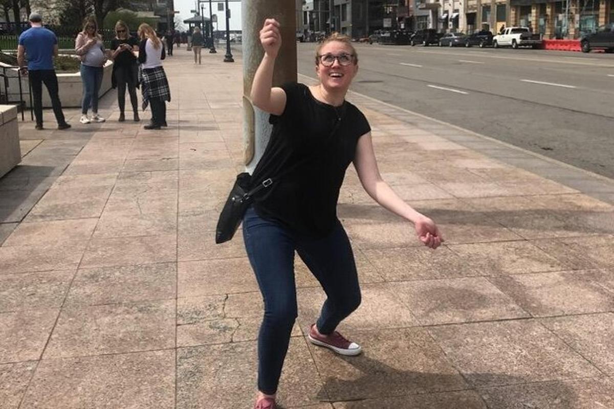 Una mujer parada en una acera con su mano en un poste