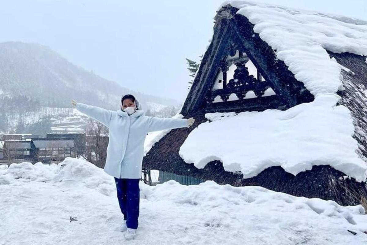 una donna in piedi nella neve davanti a un edificio