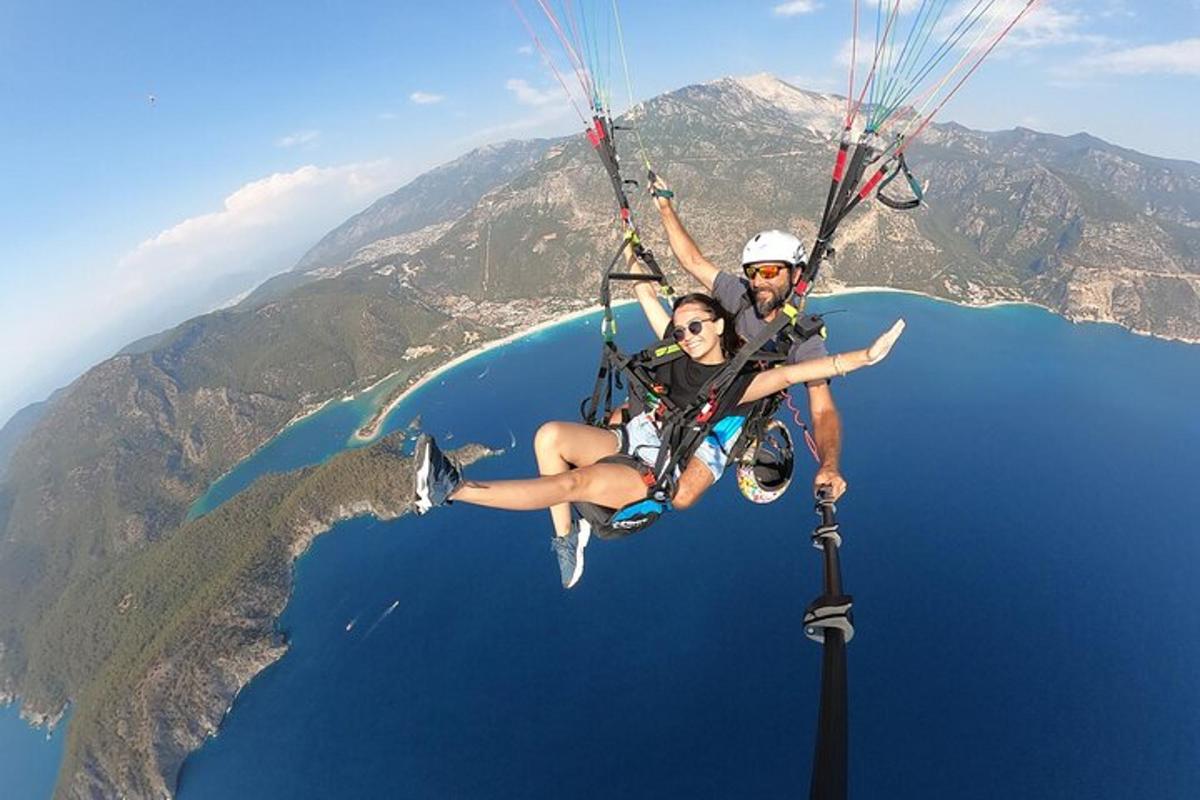 a man and woman riding a parachute over the ocean