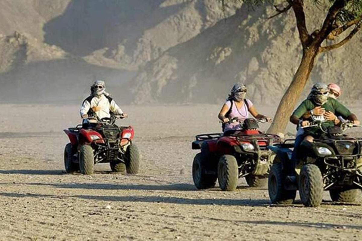 tre persone in sella a quad nel deserto